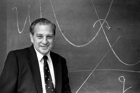 A black and white photo of Rudolph Marchs standing at a blackboard