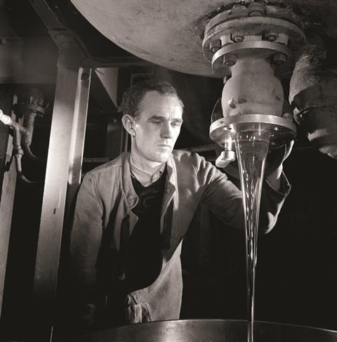 An ICI process worker watches raw silicon material pouring from vat, Ardeer, 1958