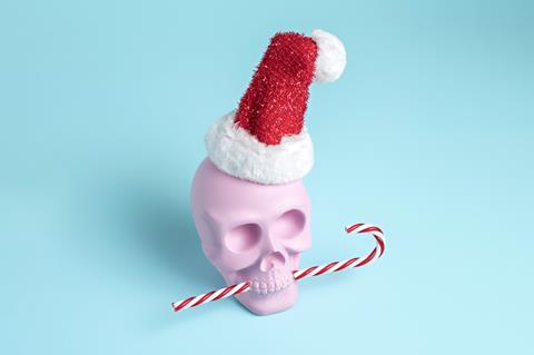 Gambar yang menunjukkan tengkorak plastik dengan topi Santa di kepalanya dan permen tongkat pepermin di mulutnya