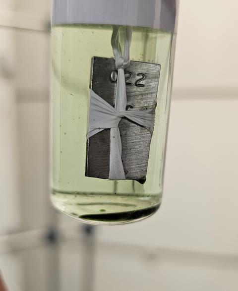 Metal coupon suspended by teflon tape in a tube full of liquid