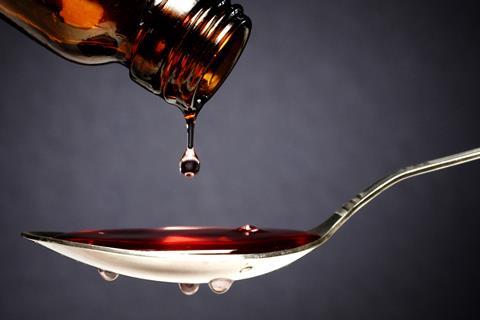Cough syrup being poured onto a spoon