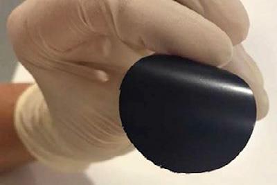 A photo of a hand holding a small circle of black material