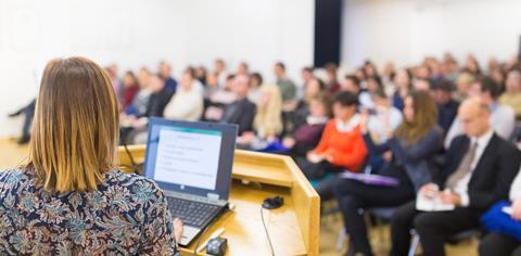 A speaker with a laptop presents to a conference audience