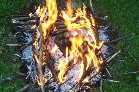 An image showing four crucibles elevated on brick and surrounded by fire