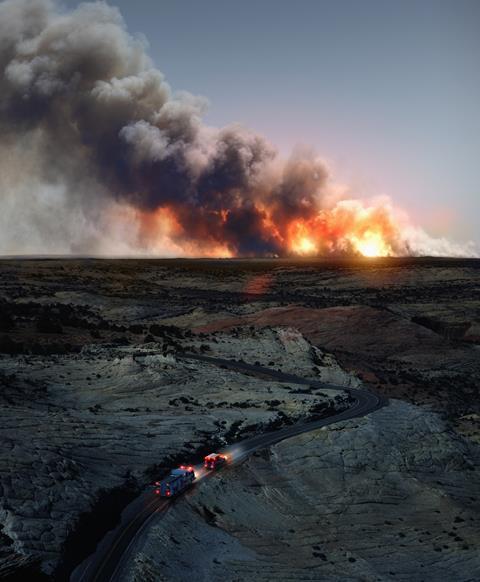 An image showing a landscape where a big wildfire can be seen on the horizon