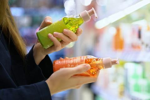 Woman examining two cosmetics bottles