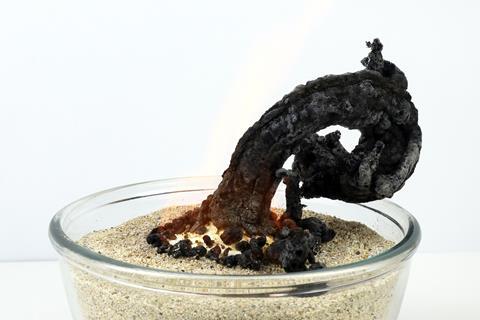 A white powder burning in a bed of sand producing a long thin black curled coal-like substance