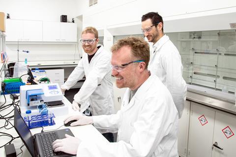 A photo of three scientists in a lab