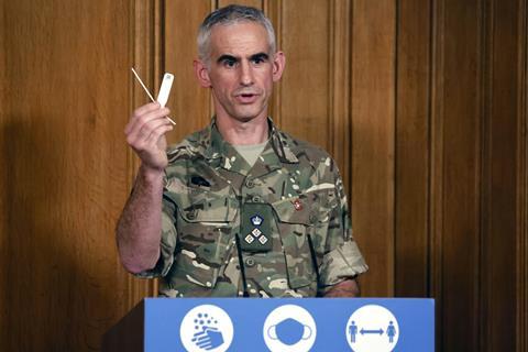 A photo of an army brigadier holding up a covid test at a press conference