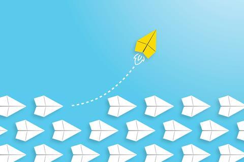 A yellow paper plane flies away from a formation of white ones