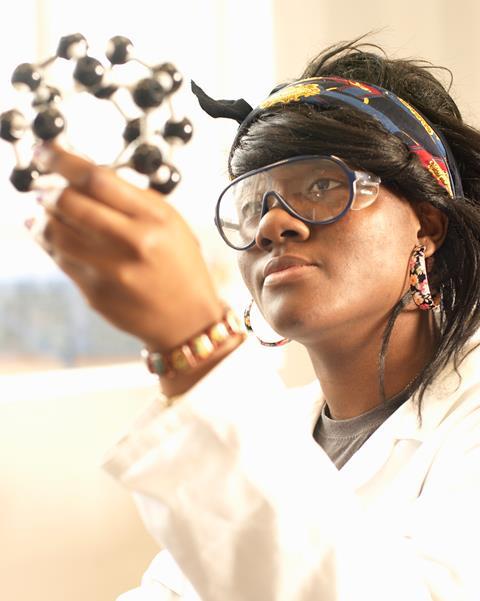 A young African American female chemistry student examines a molecular model