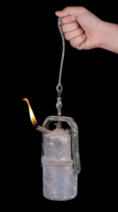 Hand holding an old mine carbide lamp 