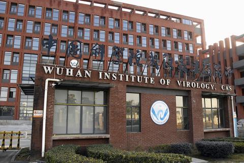A large brick office building with a sign in Chinese and a sign in English which reads Wuhan Institute of Virology, CAS