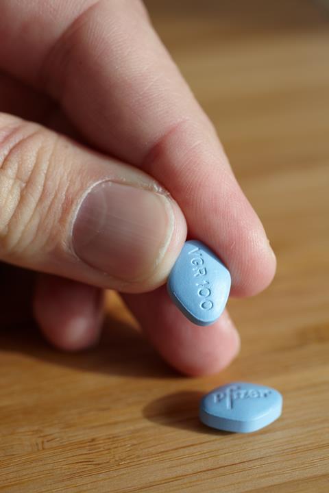 A hand holding a viagra tablet