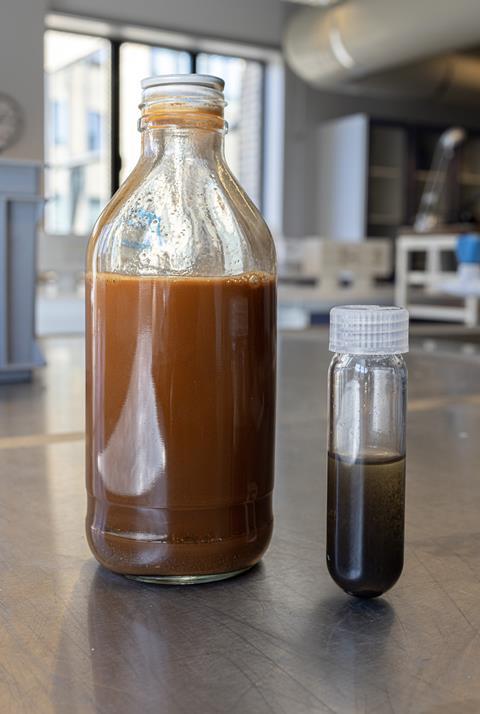 A bottle of cloudy reddish brown liquid and a vial of grey-brown liquid in a lab
