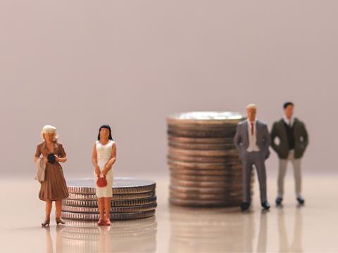 Mini male and female model figures stood near pile of coins