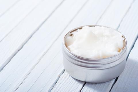 Pot of cosmetic cream on a white wooden table