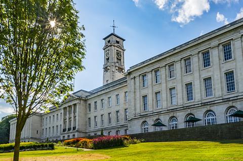 A grand white marble building with a clock tower and gardens