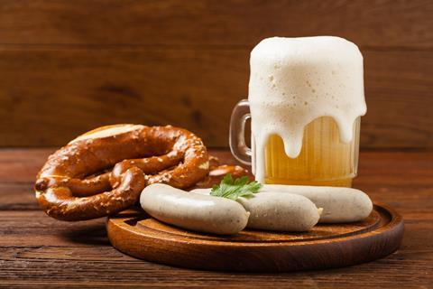A photograph of beer, white sausages and pretzels