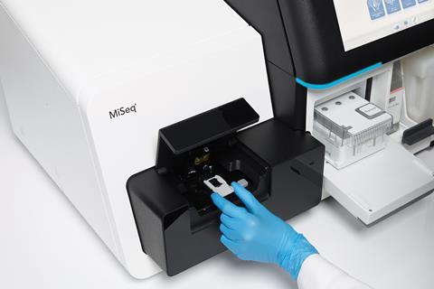A scientist loads a sample slide into a white machine