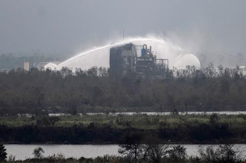 Firefighters douse the exterior of a chemical plant with water after a fire following a storm