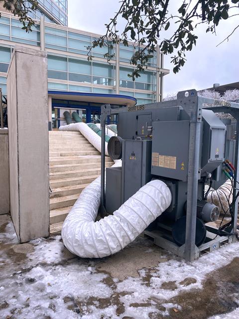 A photo of an industrial dehumidifier with pipes leading into a building