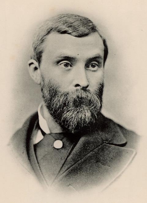 A black and white portrait photo of Thomas Lauder Brunton, a white, bearded man with short hair an an intense stare, wearing a neat suit jacket and overcoat