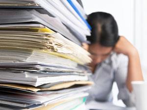 Stack of paperwork with overwhelmed lady