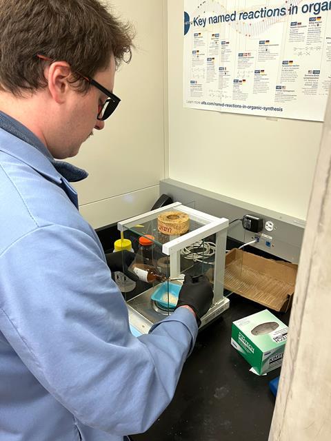 A scientist in a lab measuring out some crystals onto some scales
