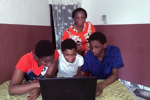A photo of a woman and three children gathered around a laptop