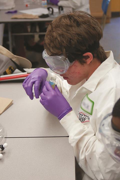 A disabled student smelling the contents of a sample vial