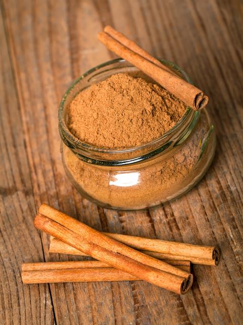 Cinnamon in transparent glass jar with cinnamon sticks on wooden table