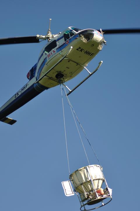 A helicopter carrying a load of 1080 pellets in a monsoon bucket, in Greymouth, New Zealand