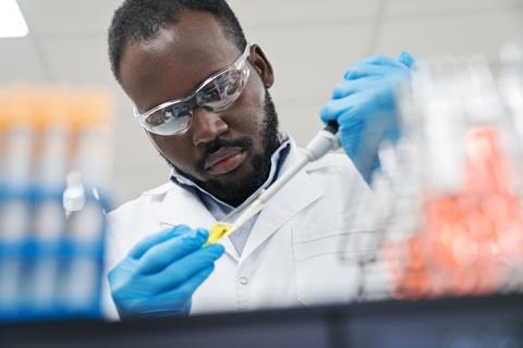 A man pipettes liquid in a lab