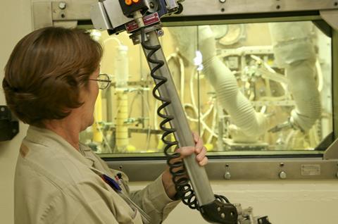0418CW - Oak Ridge Feature - ORNL worker using mechanical arm to work inside hot cell 