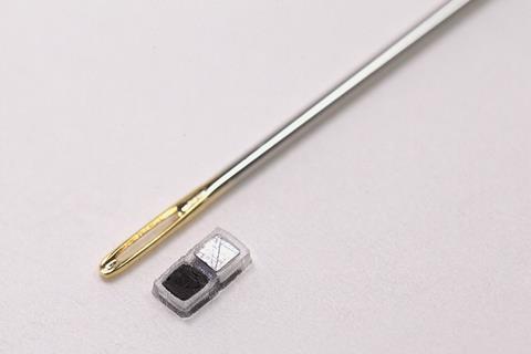 Millimeter-scale bioresorbable cardiac pacemaker next to the eye of a needle to show its tiny size