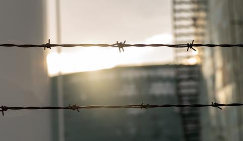 A barbed wire fence in front of a chemical plant