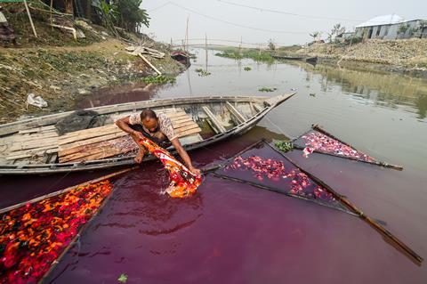 An image showing a worked washing dyed fabric in a river