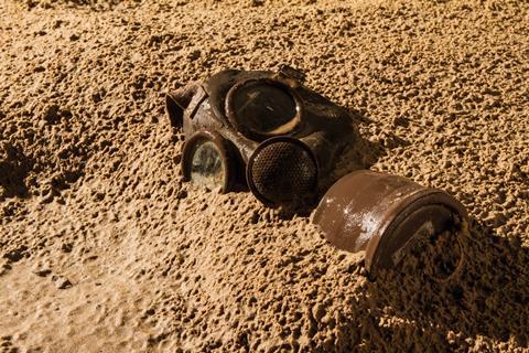 Vintage gas mask buried in the sand