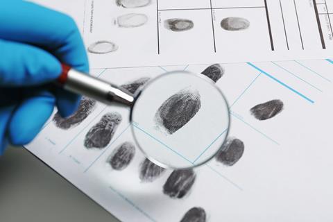 Criminologist examining fingerprints on paper