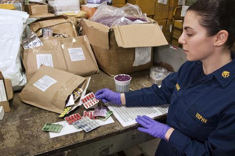 An image showing an FDA employee analysing packages pulled by CBP