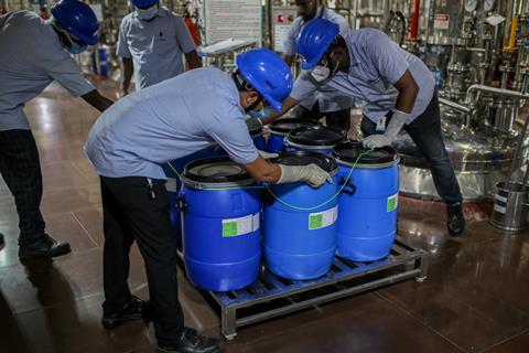 Operatives at an Indian drug manufacturing facility load barrels of product onto a pallet