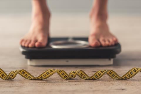 Standing on weighing scales, tape measure in foreground