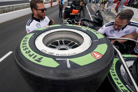 A racing car tyre with prominent green labelling stacked in the pit lane of a racing circuit