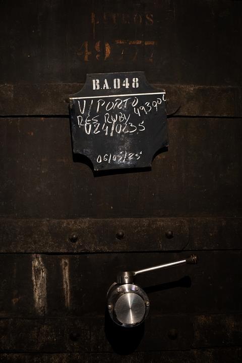 Close-up photo of a barrel with a modern steel tap and a blackboard label with numbers and dates on