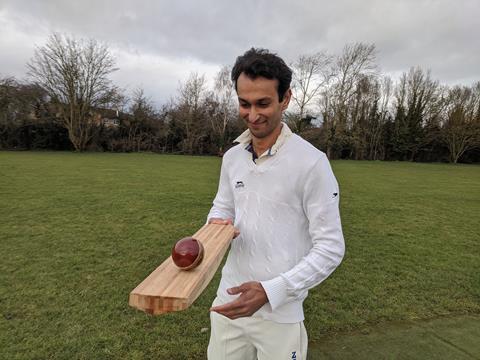 An image showing a man holding a bamboo cricket bat