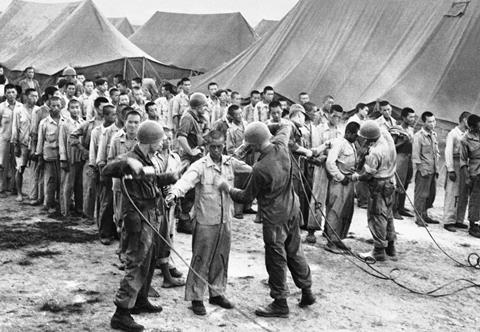 North Korean prisoners entering a POW camp in Pusan and being sprayed with DDT powder by US soldiers