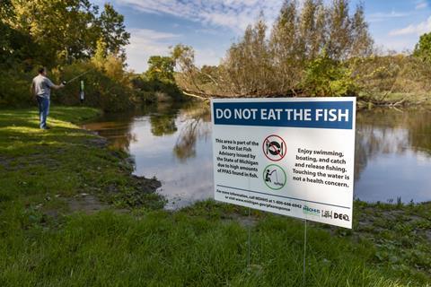 An image showing a sign that warns against eating the fish inside a river, as it is contaminated with PFAS
