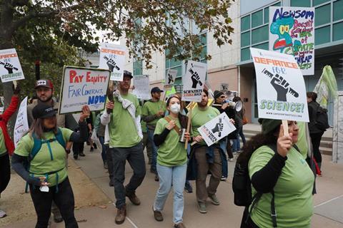 Scientists protesting with placards for pay equity