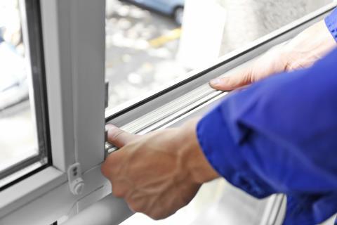 Construction worker putting sealing foam tape on window in house 